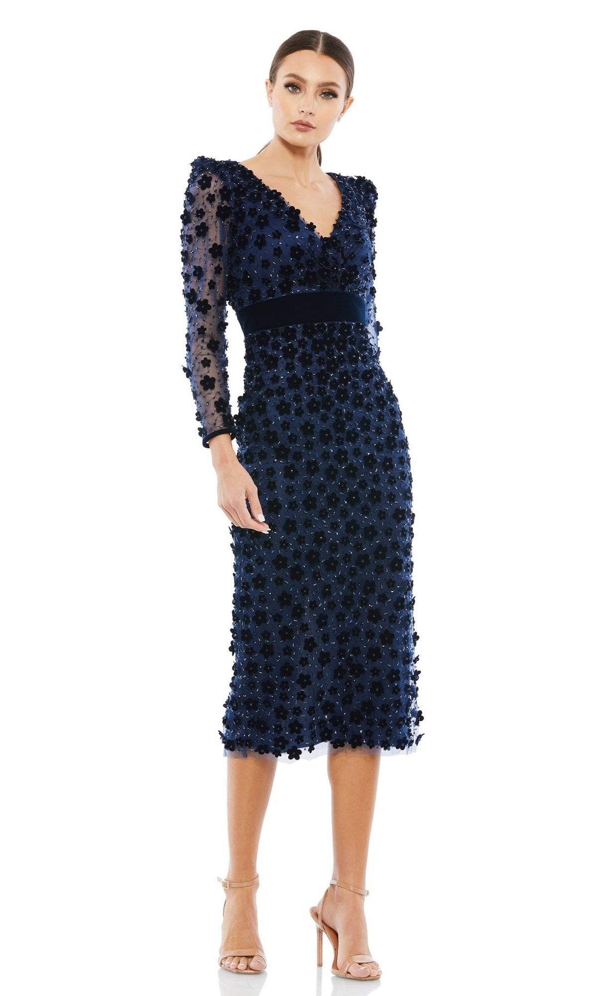 A woman wears the Short Wedding Guest Dress 67856 by Mac Duggal—a knee-length navy floral V-neck dress with long sleeves—styled with nude heels for a perfect semi-formal wedding guest look.
